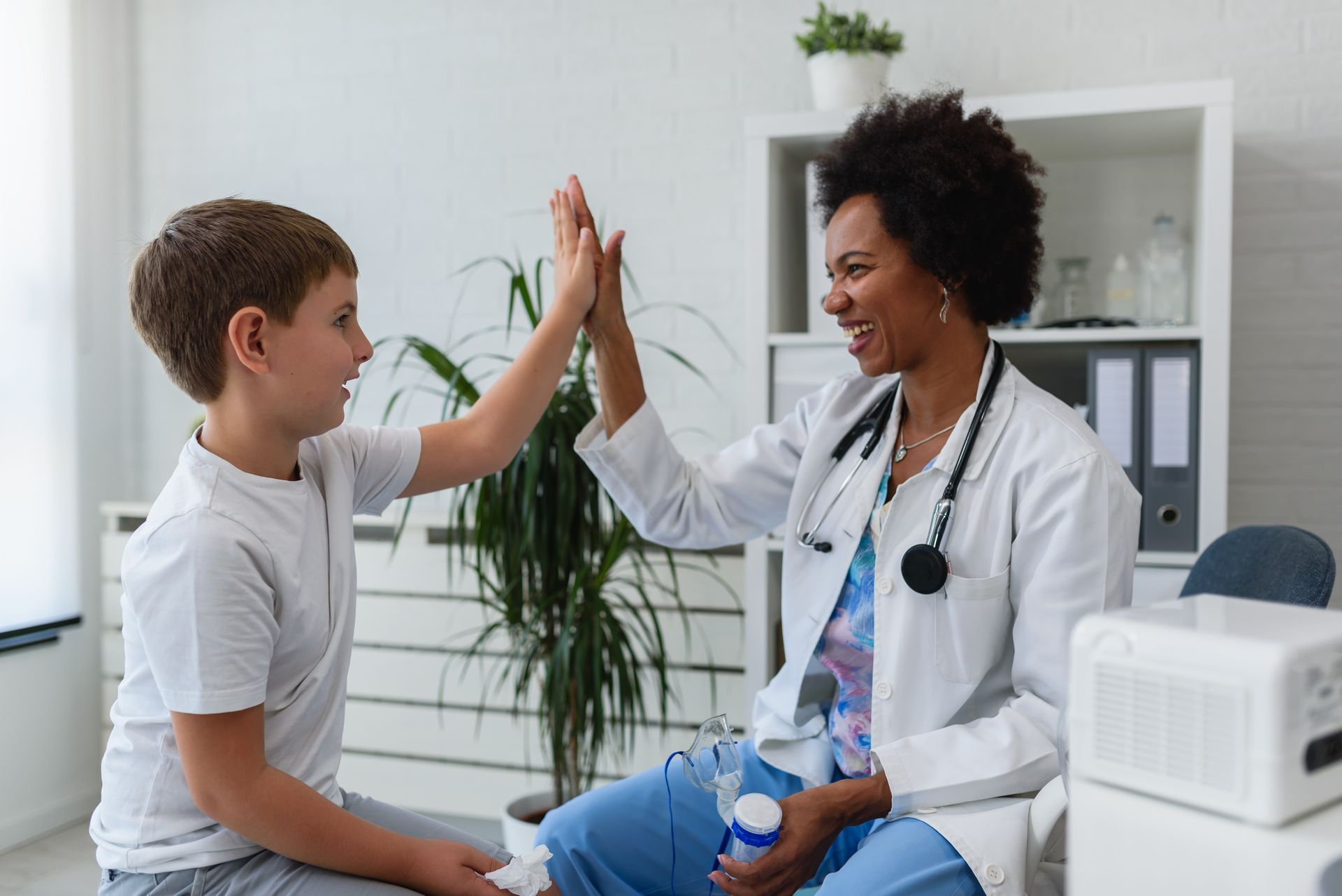Doctor general practitioner talks and amuses child before medical examination