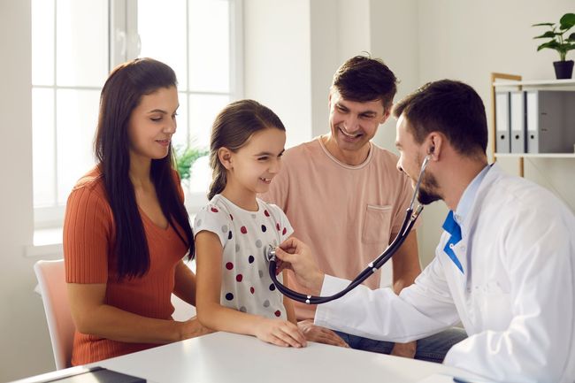 Doctor puts a stethoscope to the little girl's chest and listens to the heartbeat and lungs