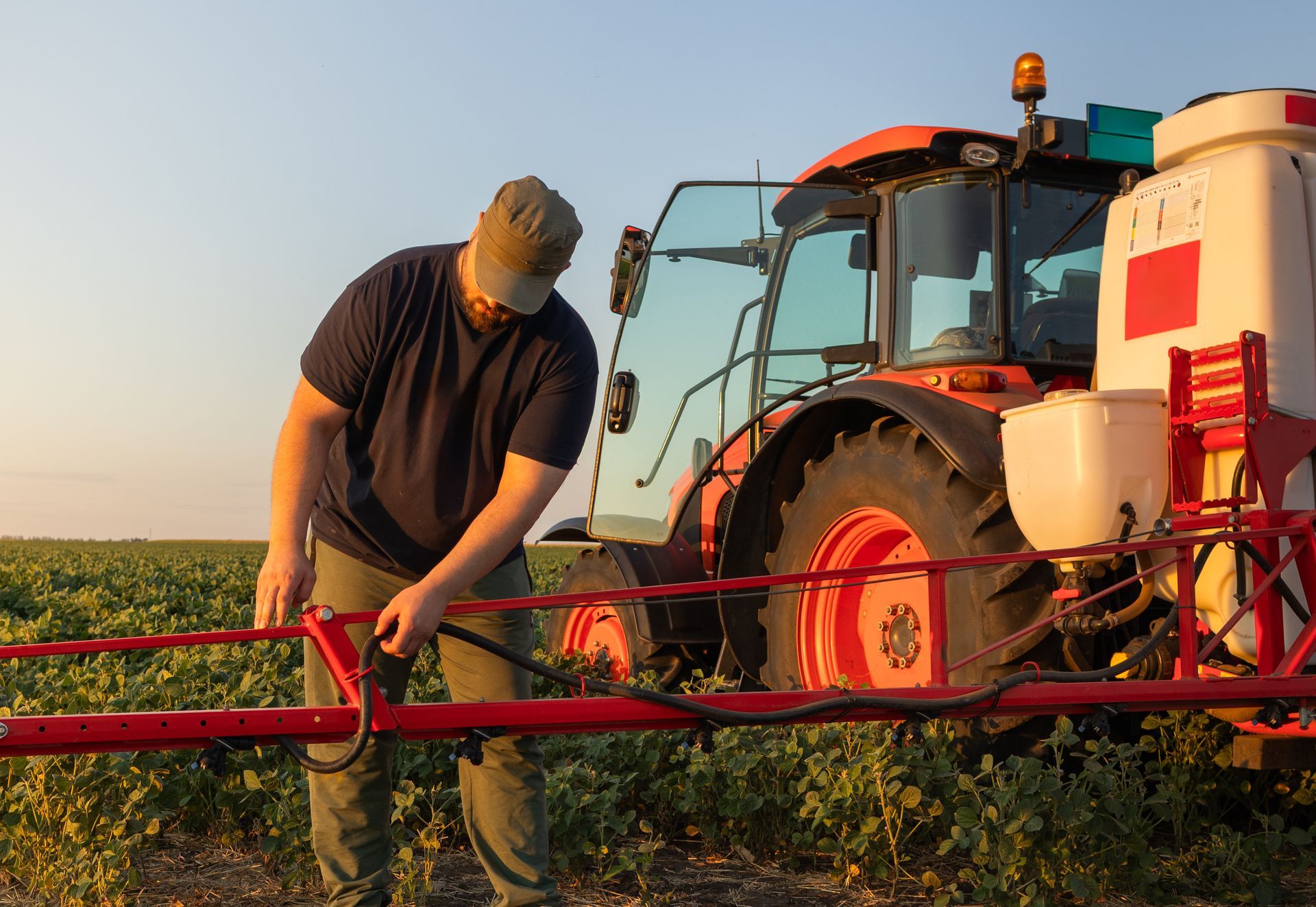 A farmer working on a tractor sprayer for plant protection, preparing for work. A farmer working on a tractor sprayer for plant protection, preparing for work.