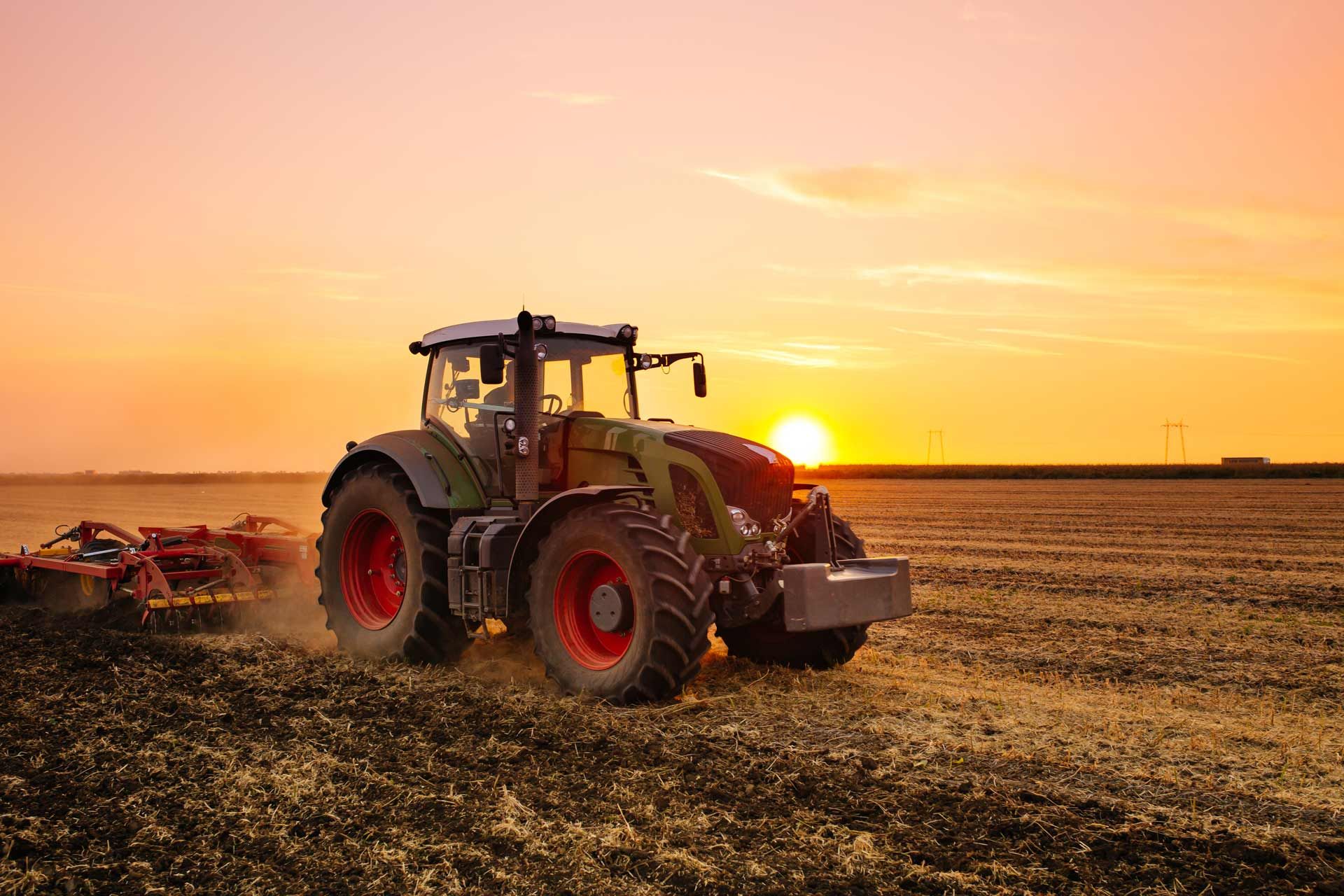A farm tractor on the barley field by the sunset. A farm tractor on the barley field by the sunset.