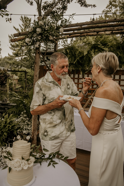Two people exchanging a toast under a leafy garden pergola