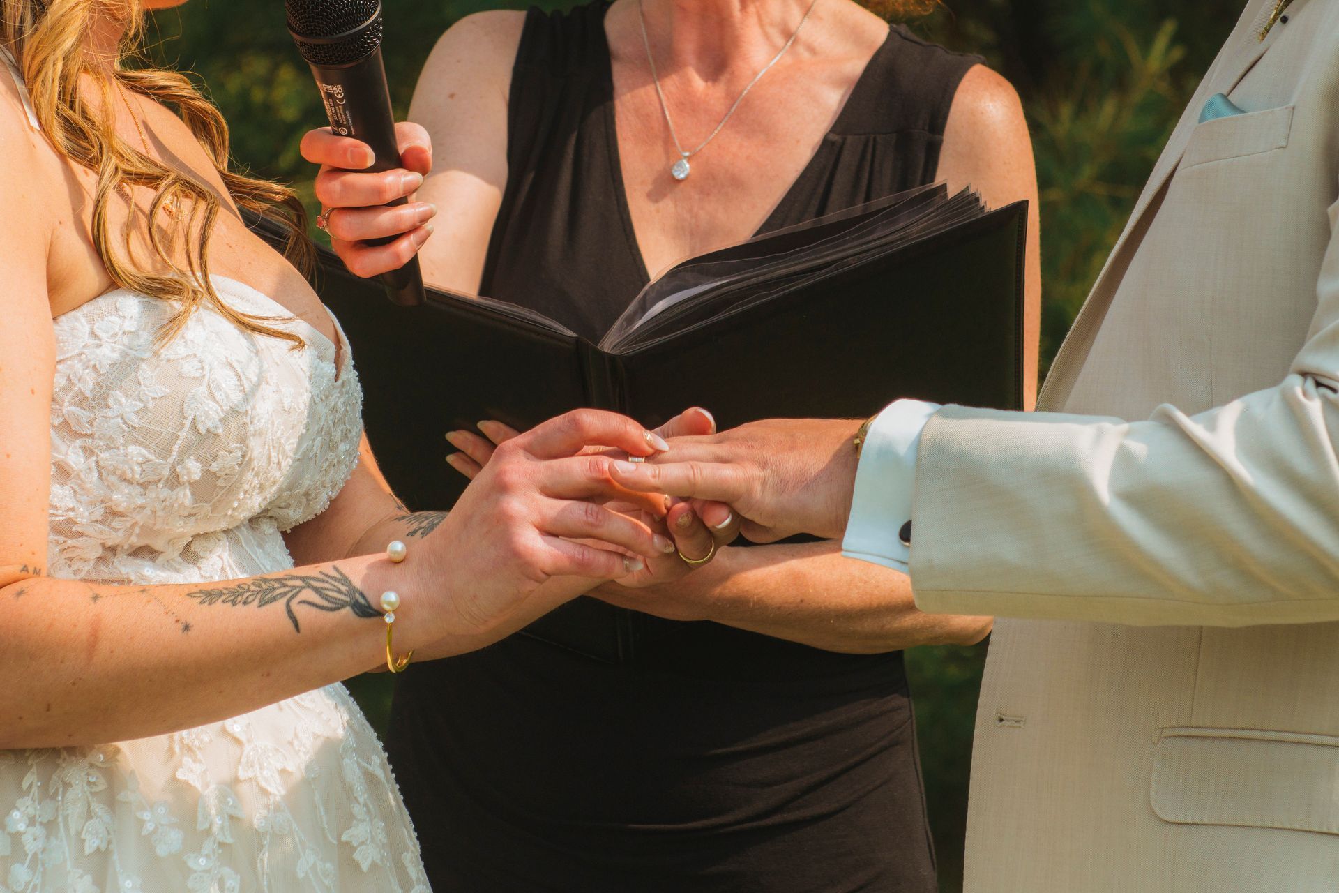 Wedding ceremony with two people holding hands as an officiant speaks into a microphone