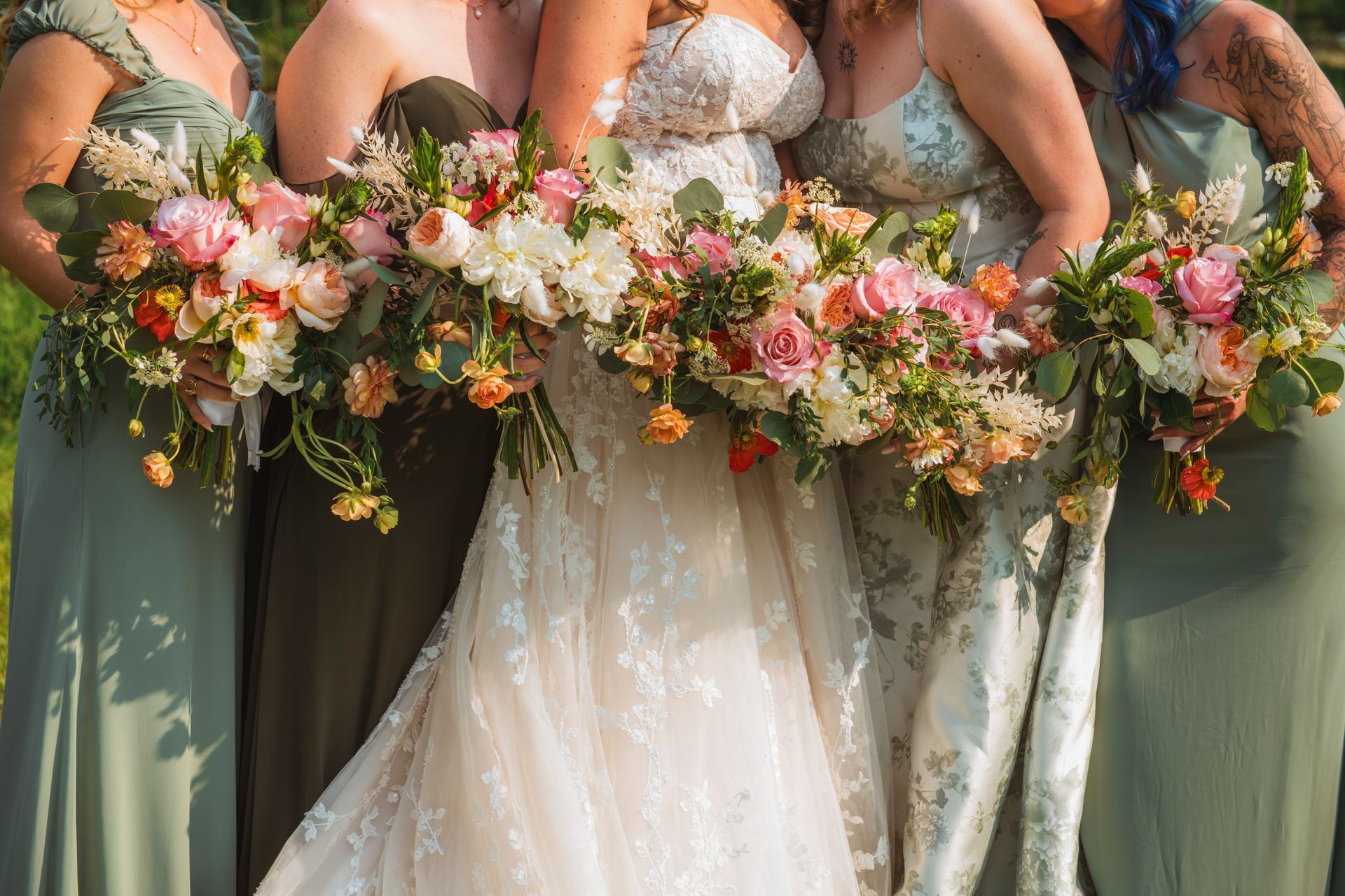Bridesmaids holding lush pink, white, and green floral bouquets in a wedding lineup