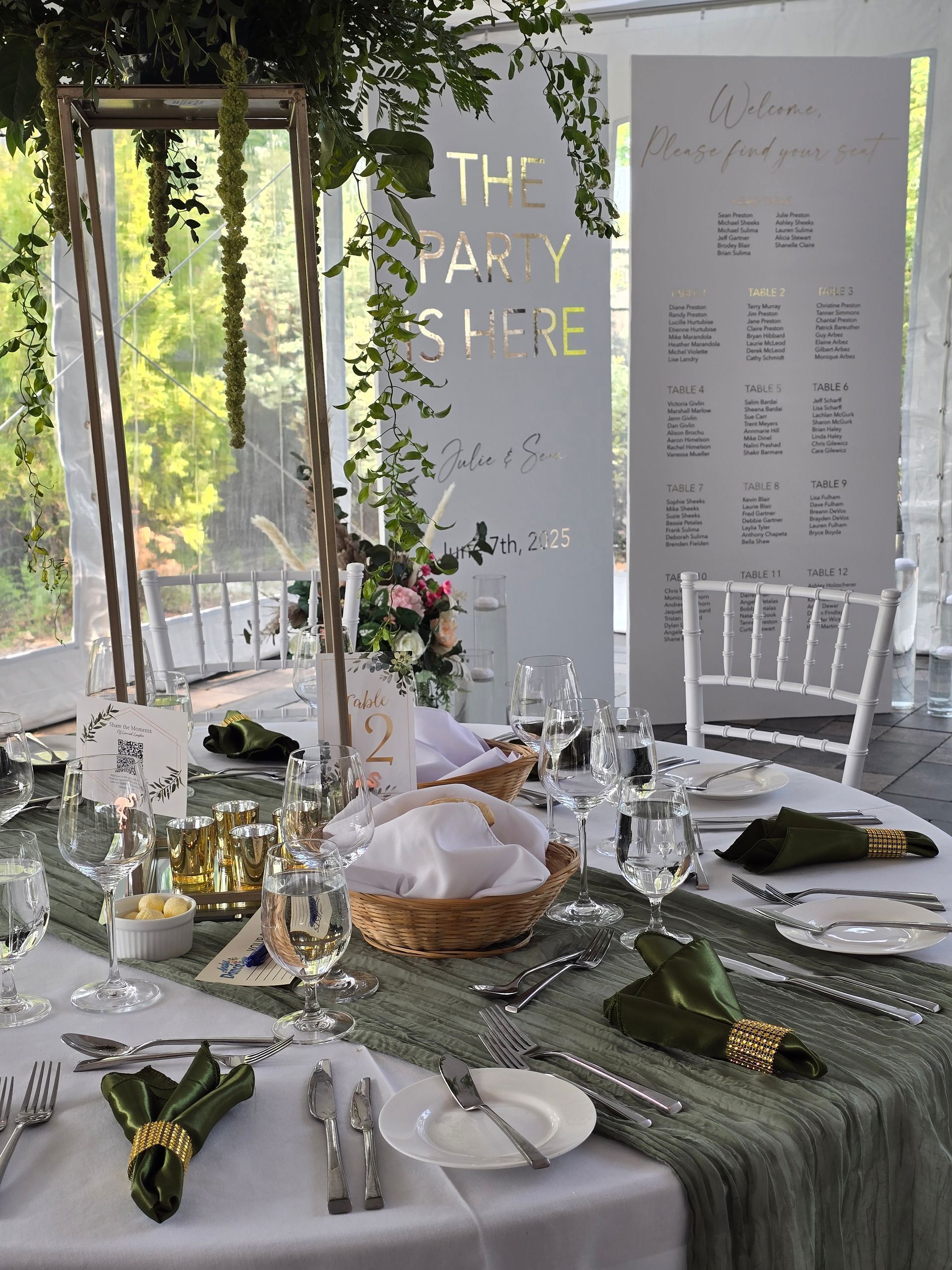 Elegant outdoor table setting with white chairs, greenery, candles, and gold-accented place settings