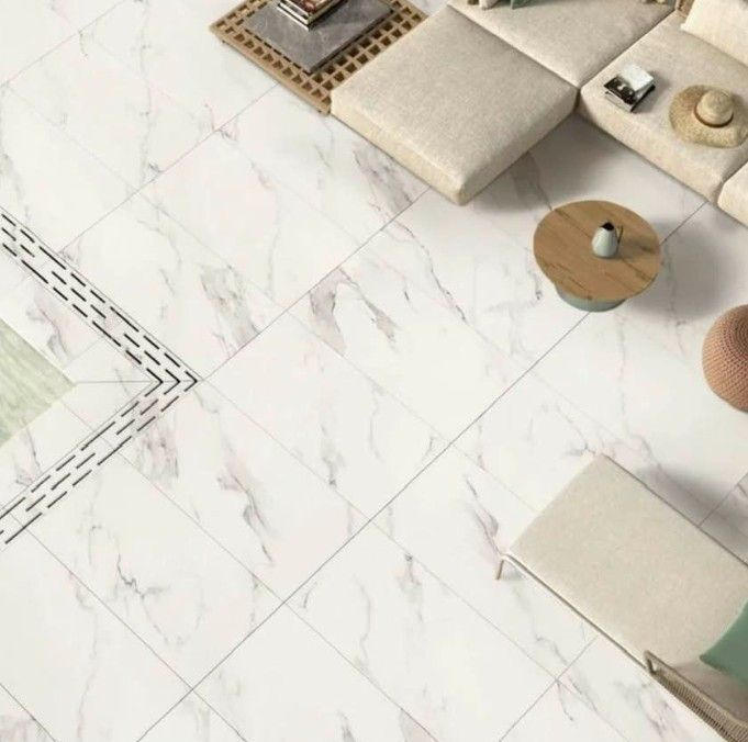 Sedute minimaliste color beige su un pavimento in marmo bianco con sottili venature grigie.