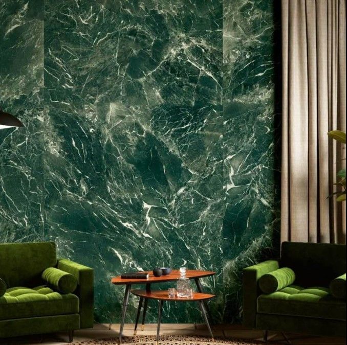 Salotto moderno con parete in marmo verde smeraldo, poltrone in velluto e tavolino da caffè in vetro.