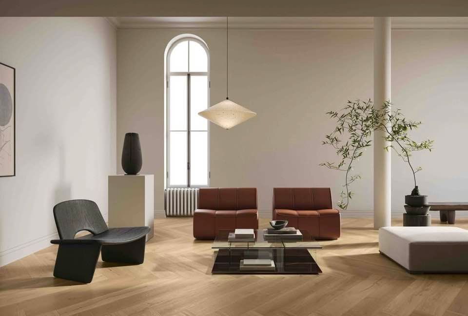 Soggiorno moderno e minimalista con divani marroni, poltrona nera, tavolino basso, ampia finestra ad arco e pianta da interno.
