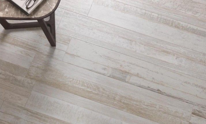 Pavimento in assi di legno chiaro con una sedia parzialmente in legno nell'angolo in alto a sinistra.