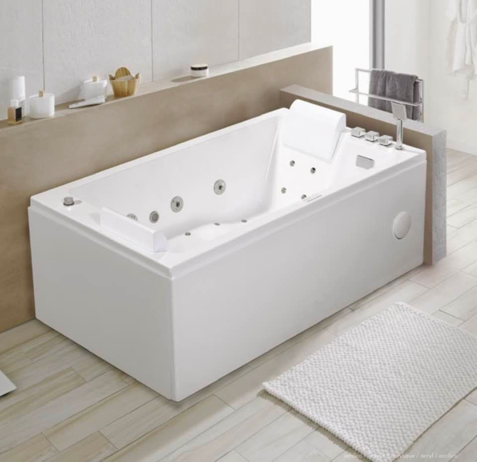 Vasca da bagno moderna bianca freestanding in un bagno luminoso e minimalista con pavimento in legno chiaro e tappetino da bagno.