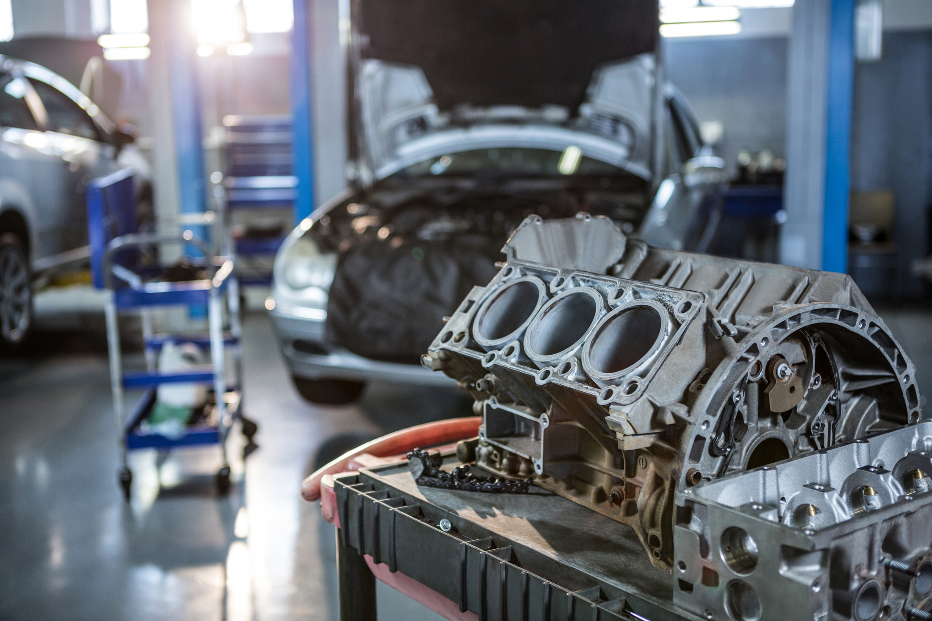 Er wordt in een garage aan een automotor gewerkt.