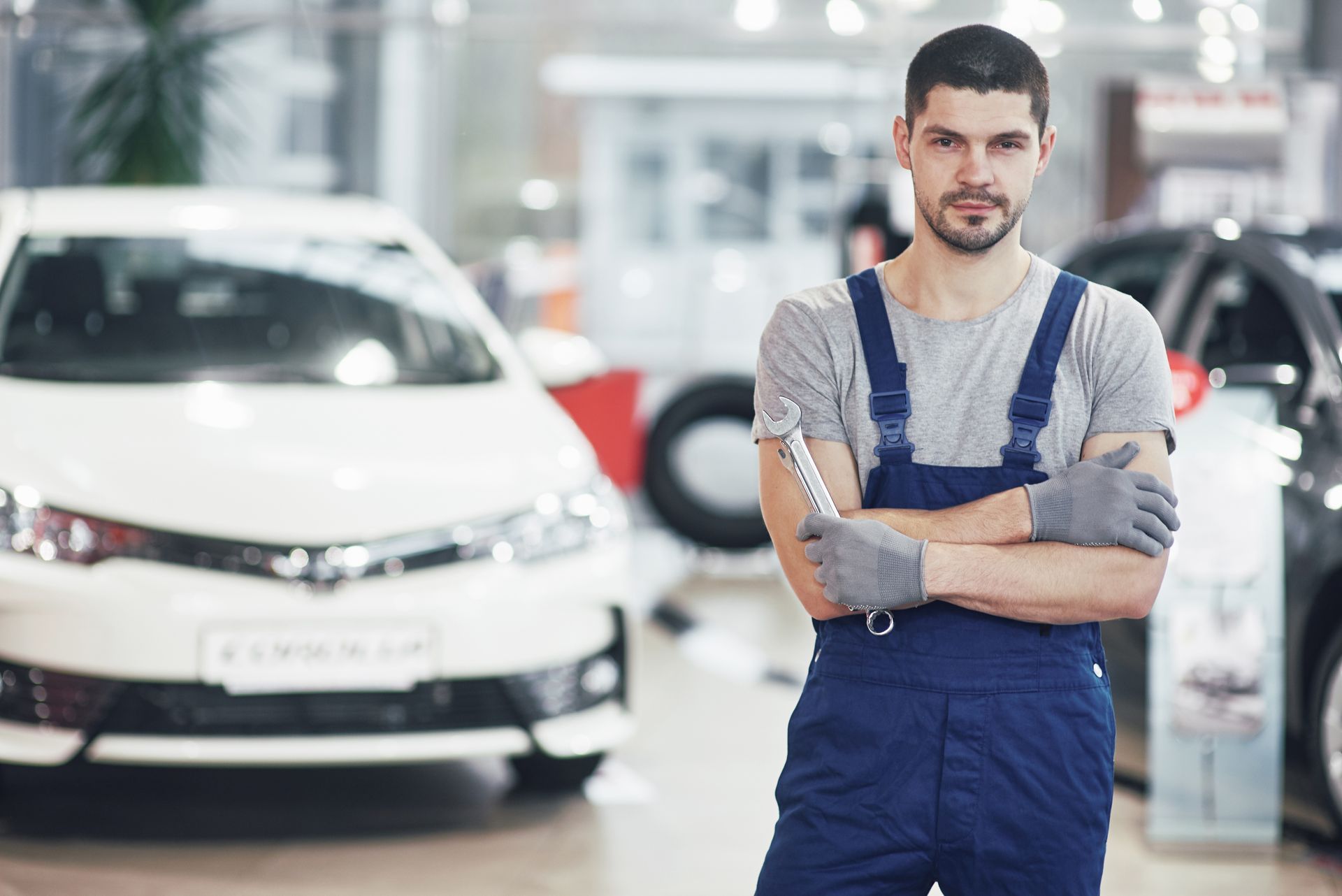 Een man in een overall staat voor een auto in een showroom.