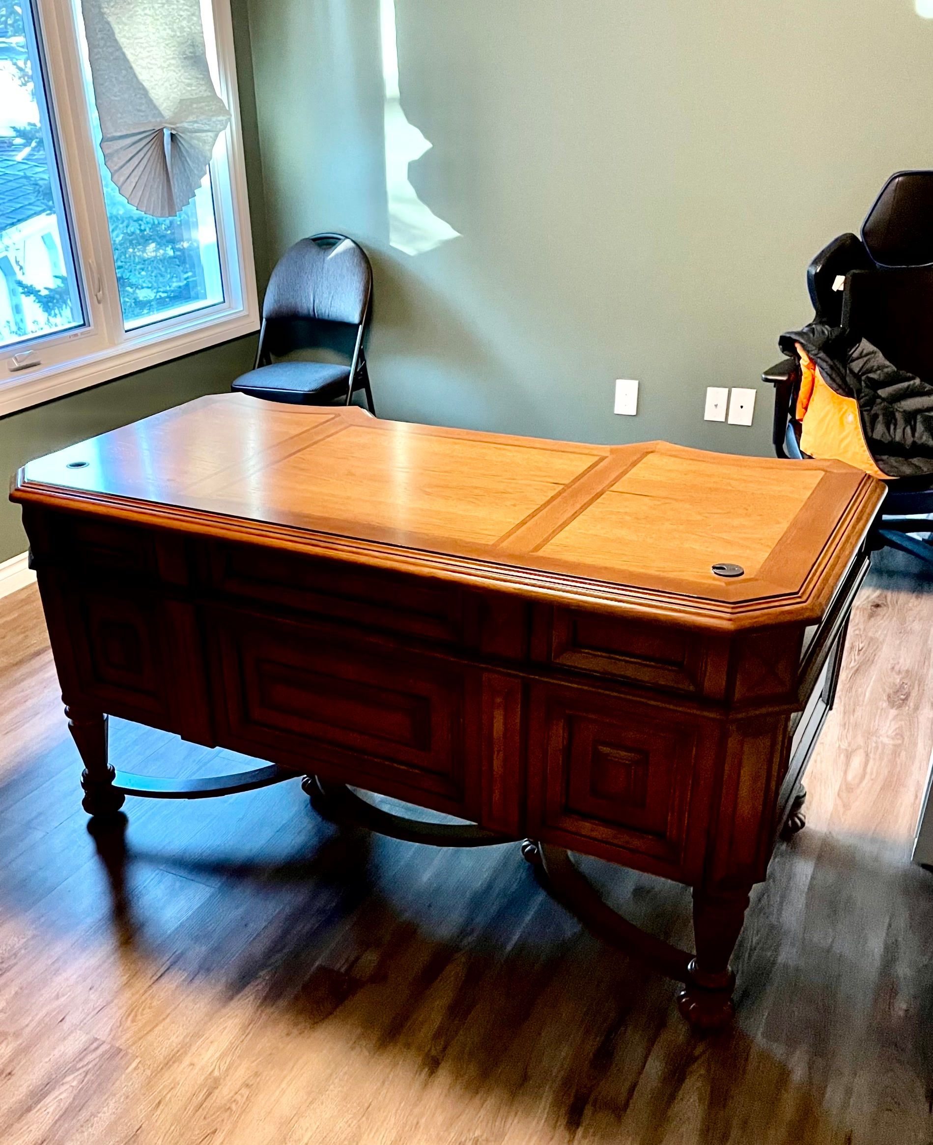 A wooden desk is sitting in a room next to a chair.