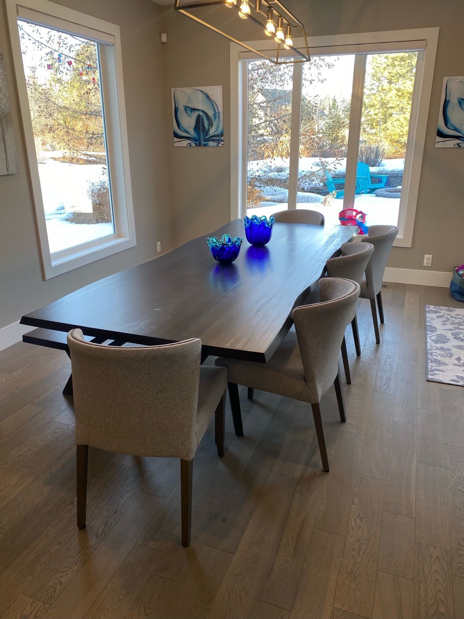 A dining room with a table and chairs and a large window.