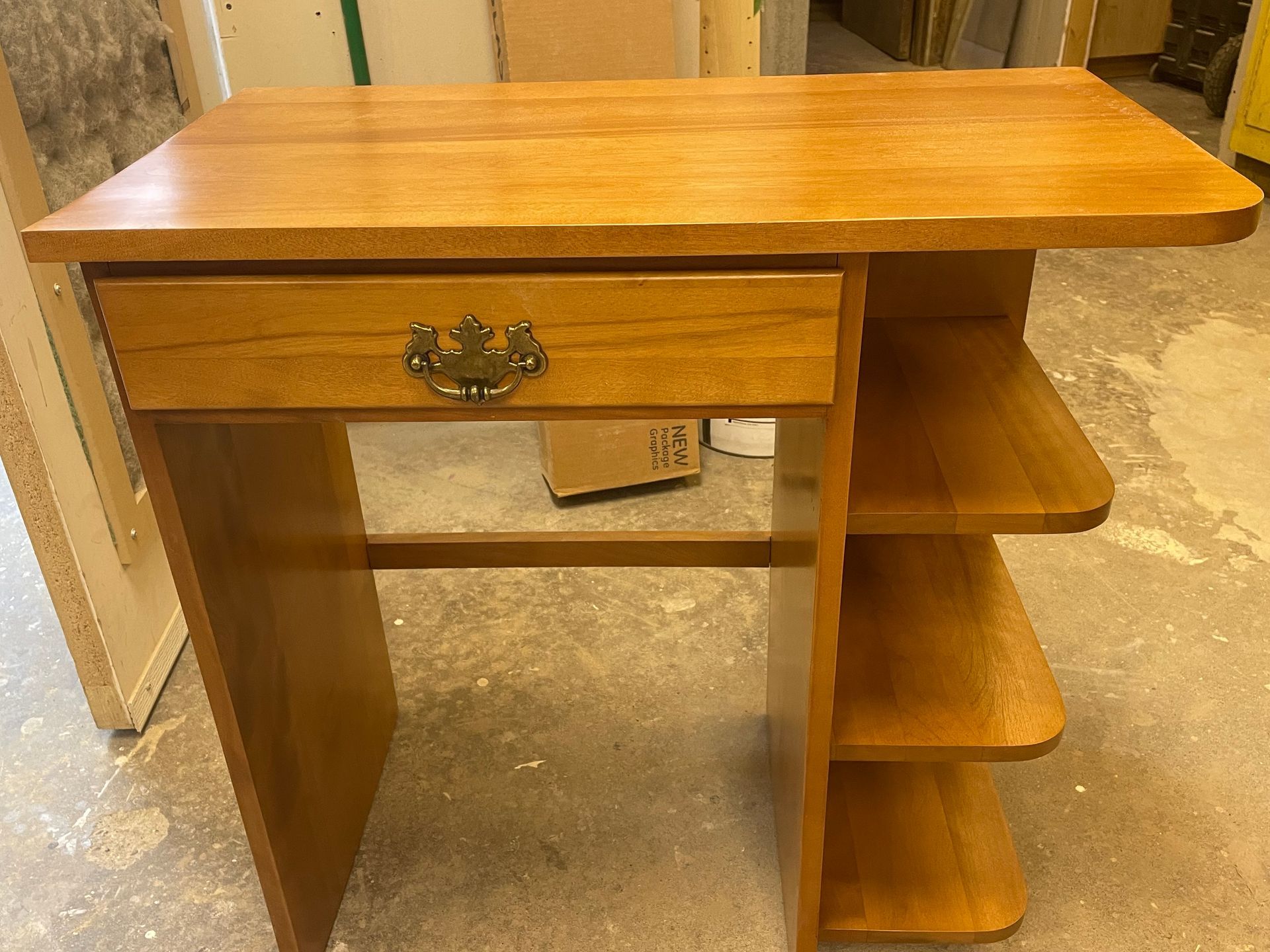 A small wooden desk with a drawer and shelves
