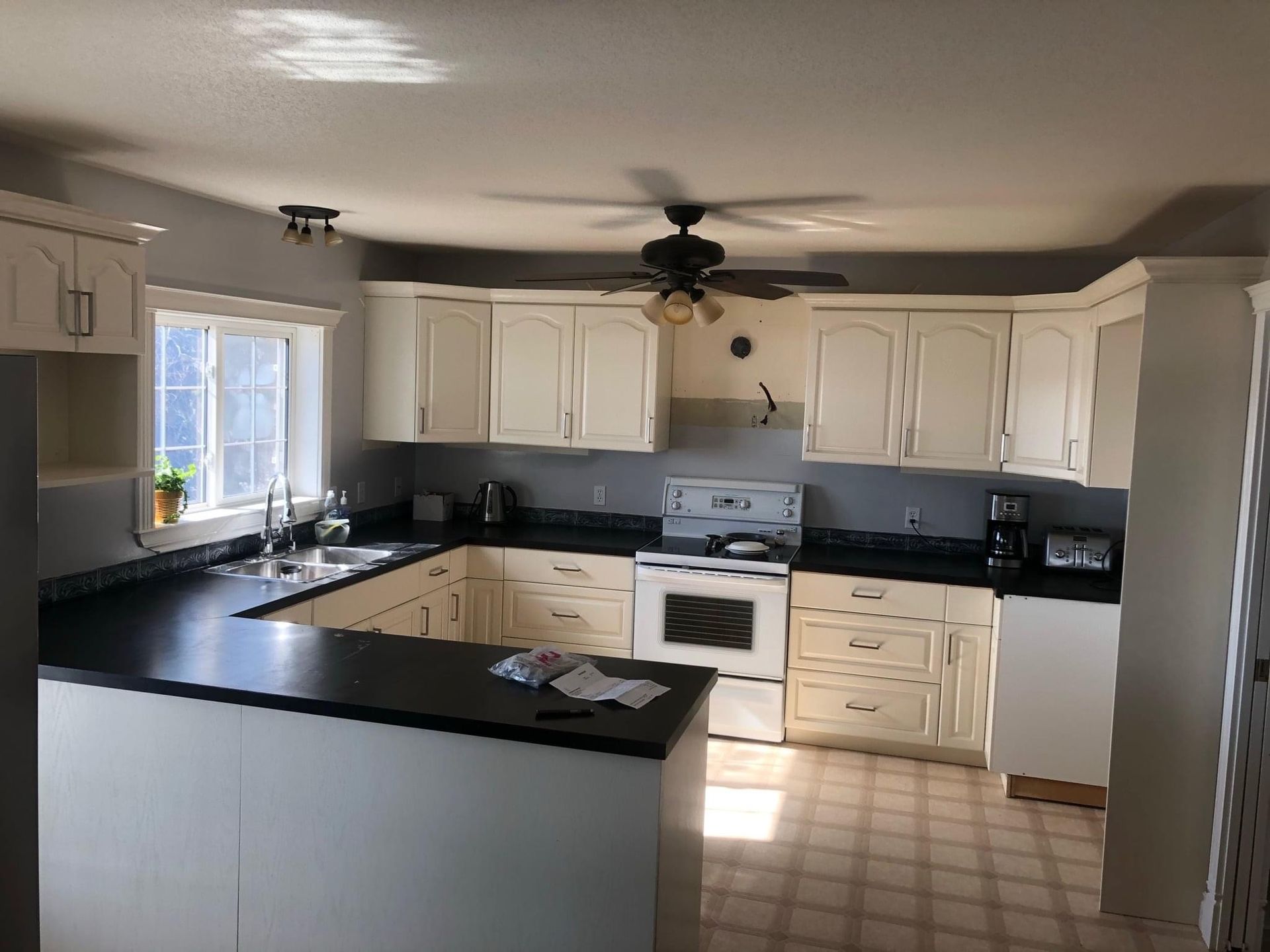 A kitchen with white cabinets and black counter tops