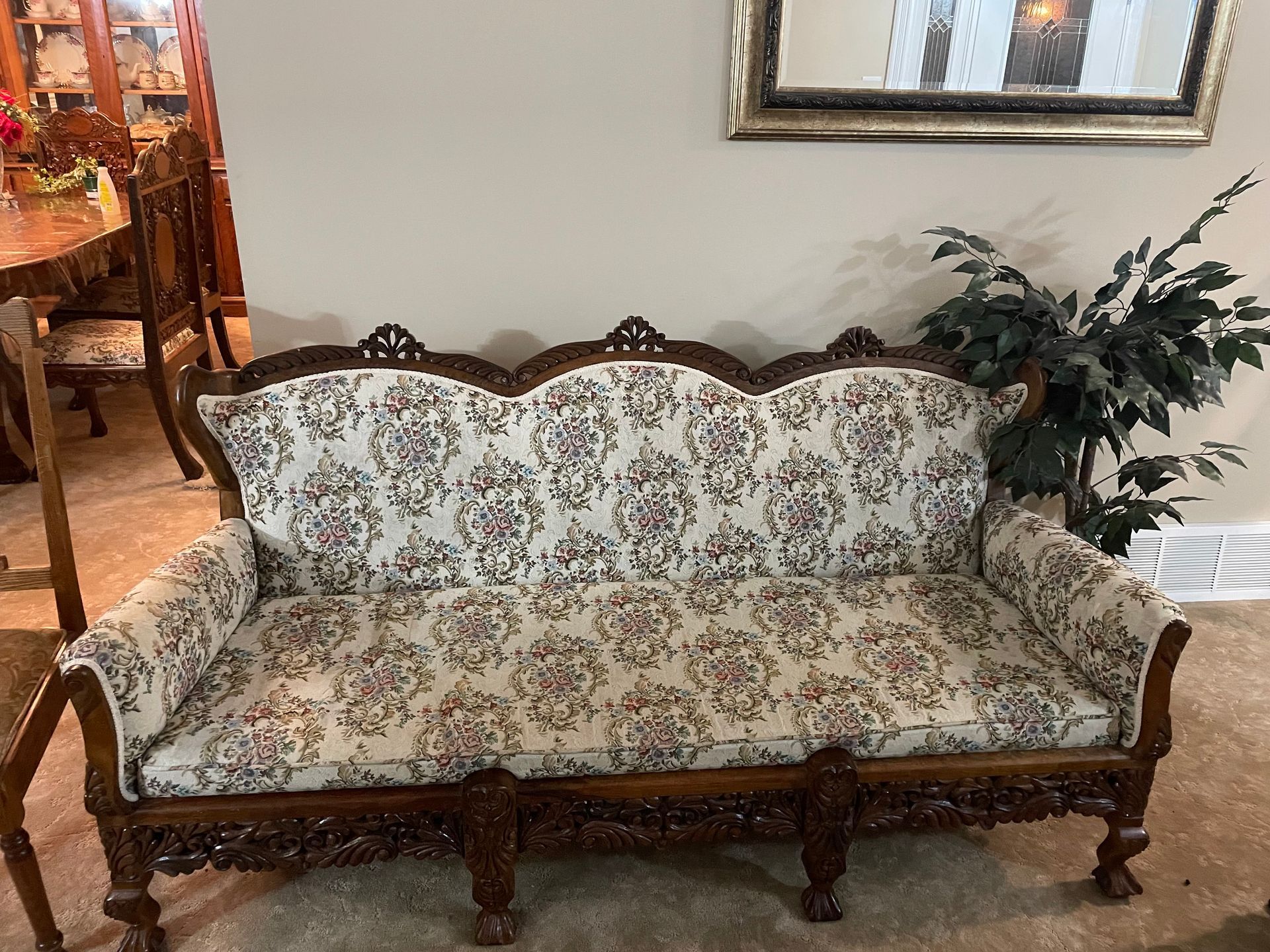 A couch is sitting in a living room next to a plant.