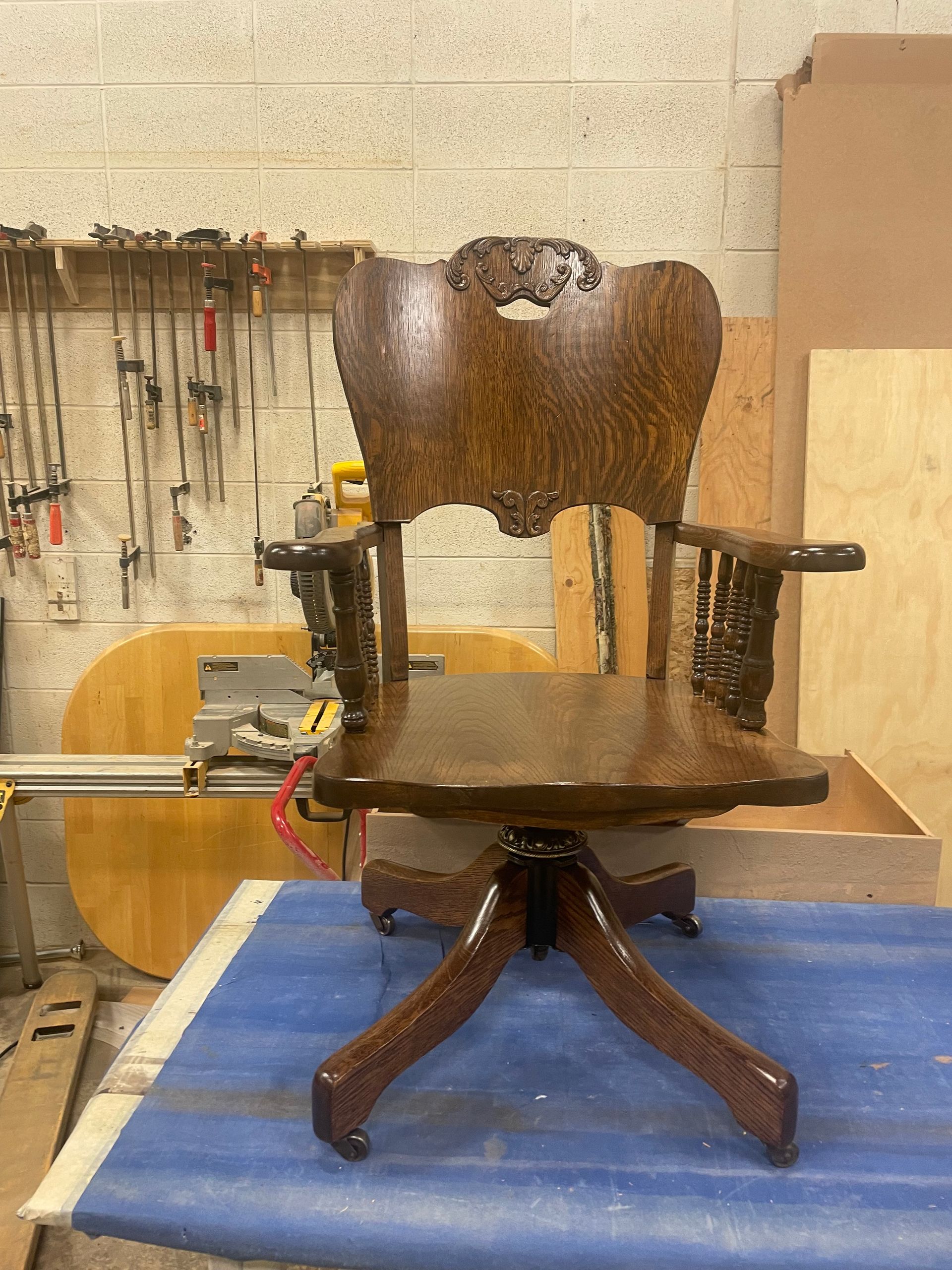 A wooden chair is sitting on top of a blue table in a workshop.