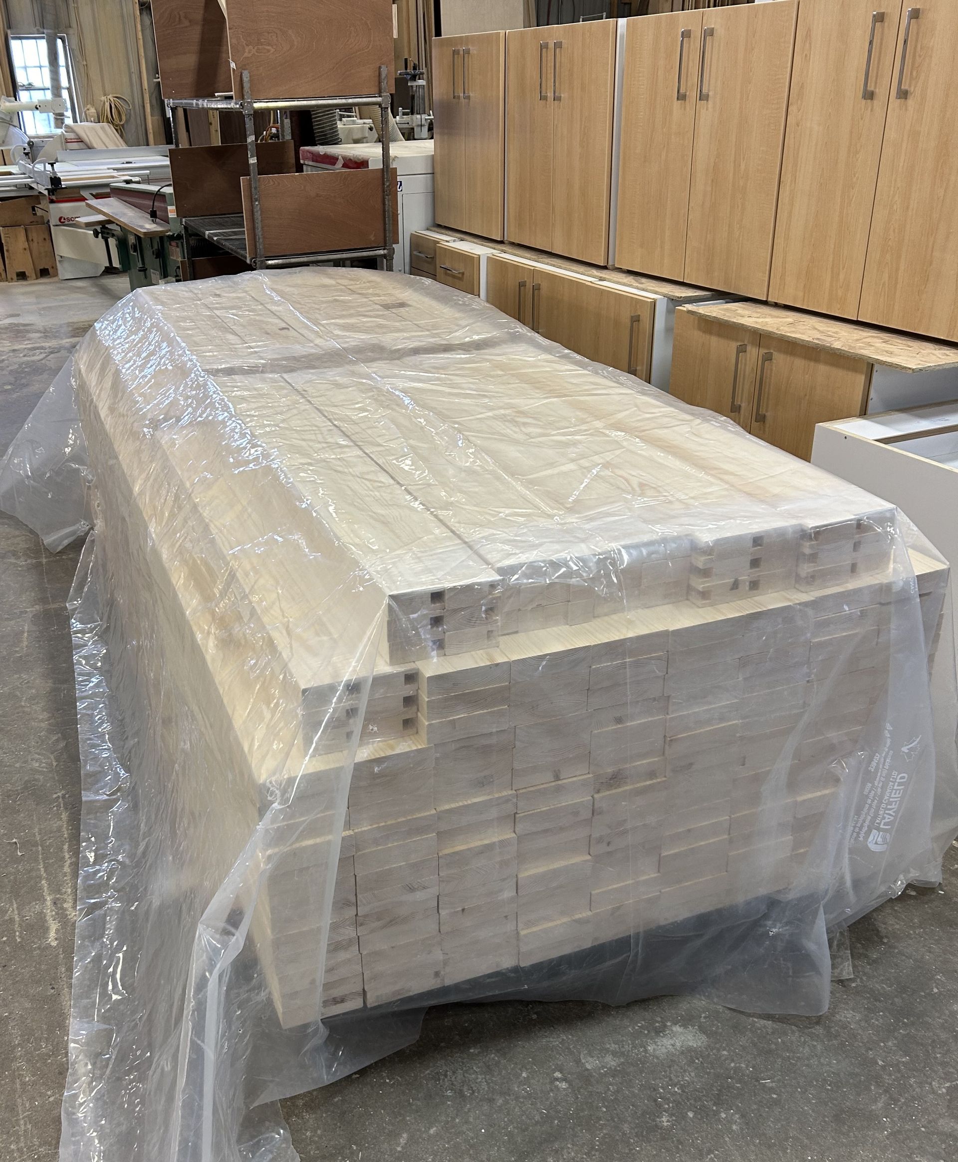 A large stack of wood is wrapped in plastic