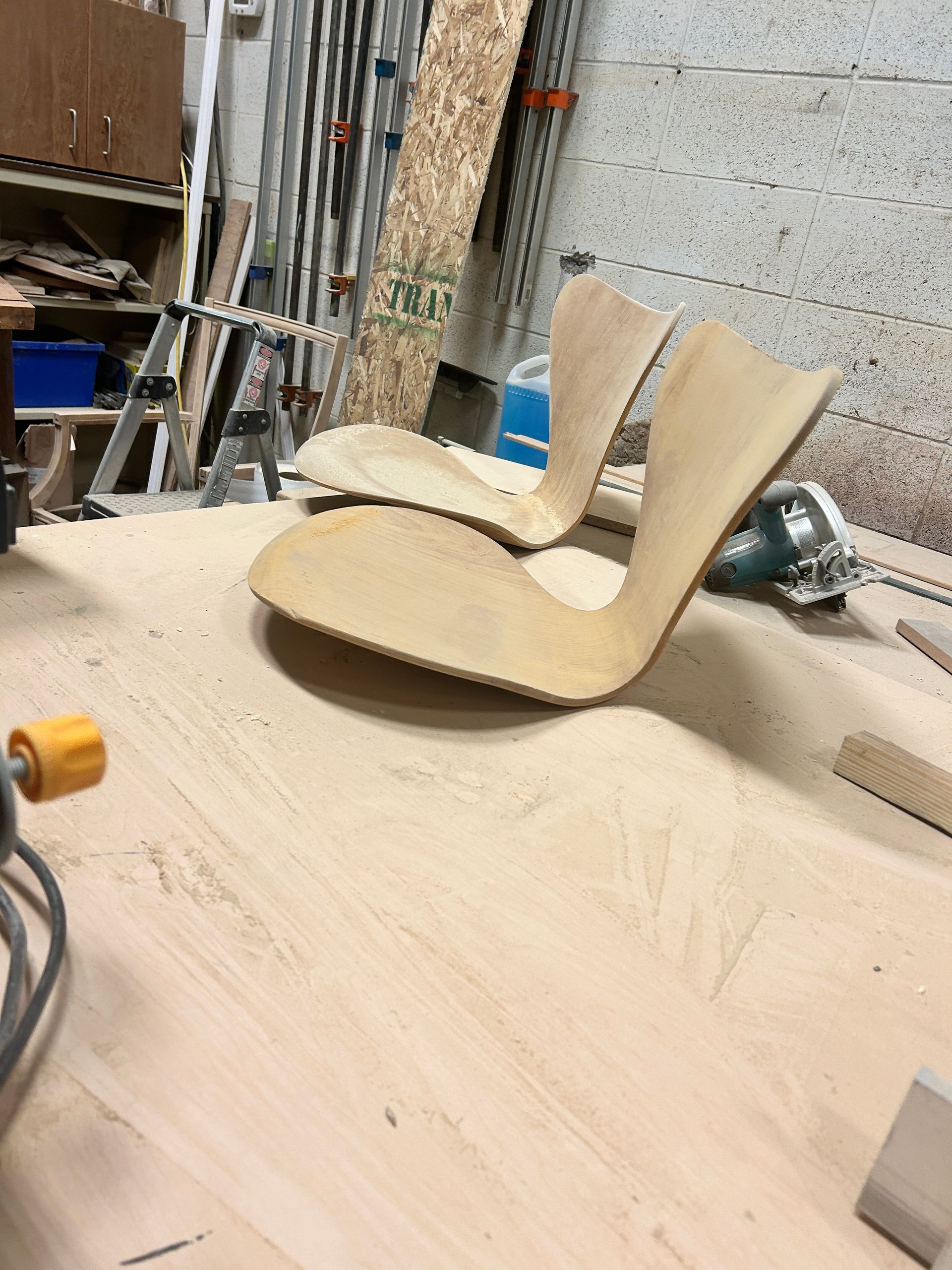 Two wooden chairs are sitting on a wooden table in a workshop.