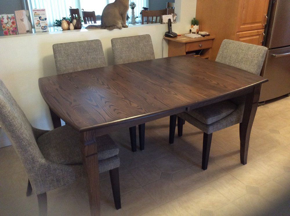 A dining room table with chairs and a cat in the background