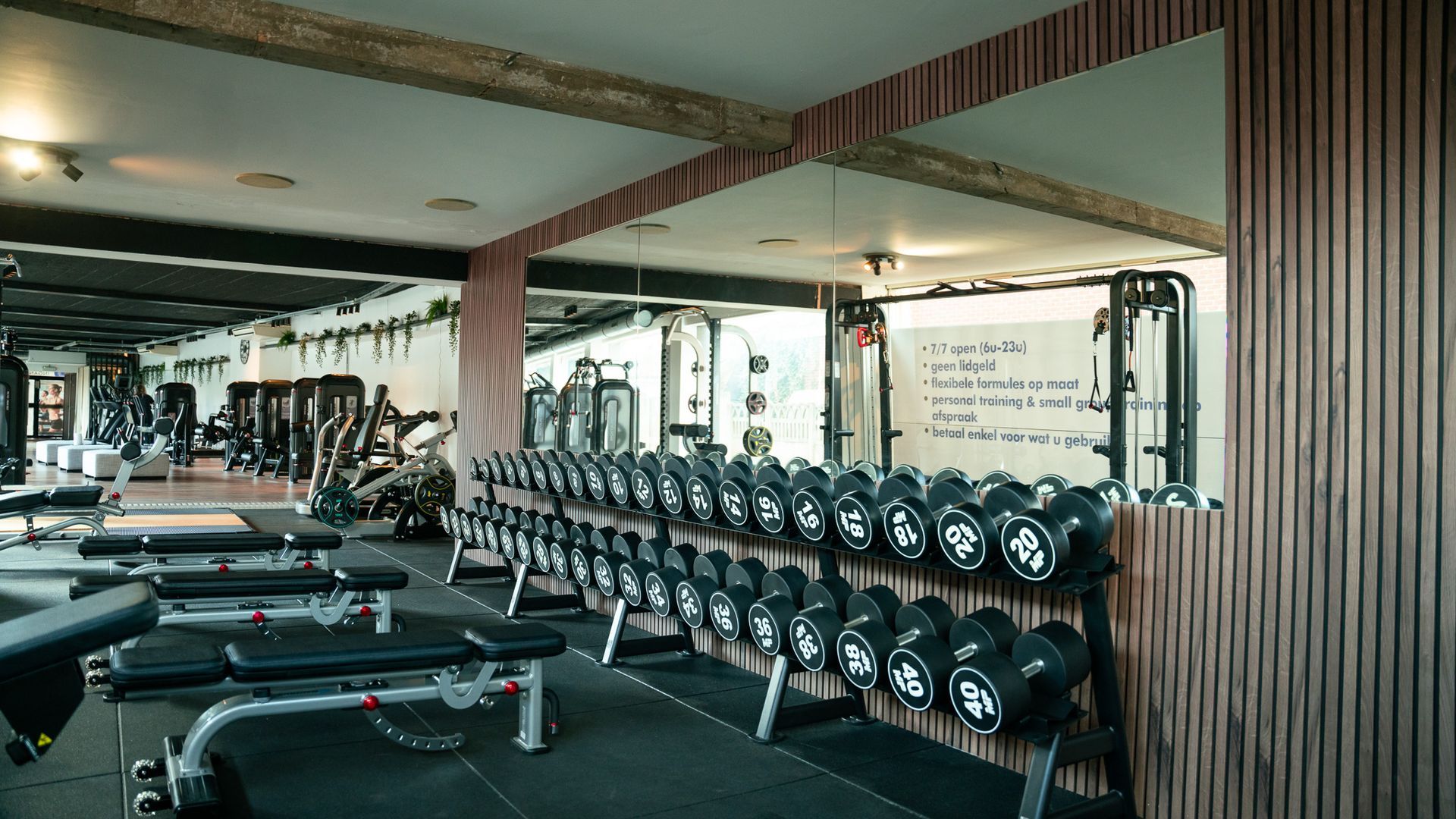 Een sportschool vol met halters en banken.