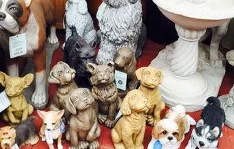 Assorted decorative dog and cat figurines displayed on a shelf, including small puppies and a white pedestal bowl