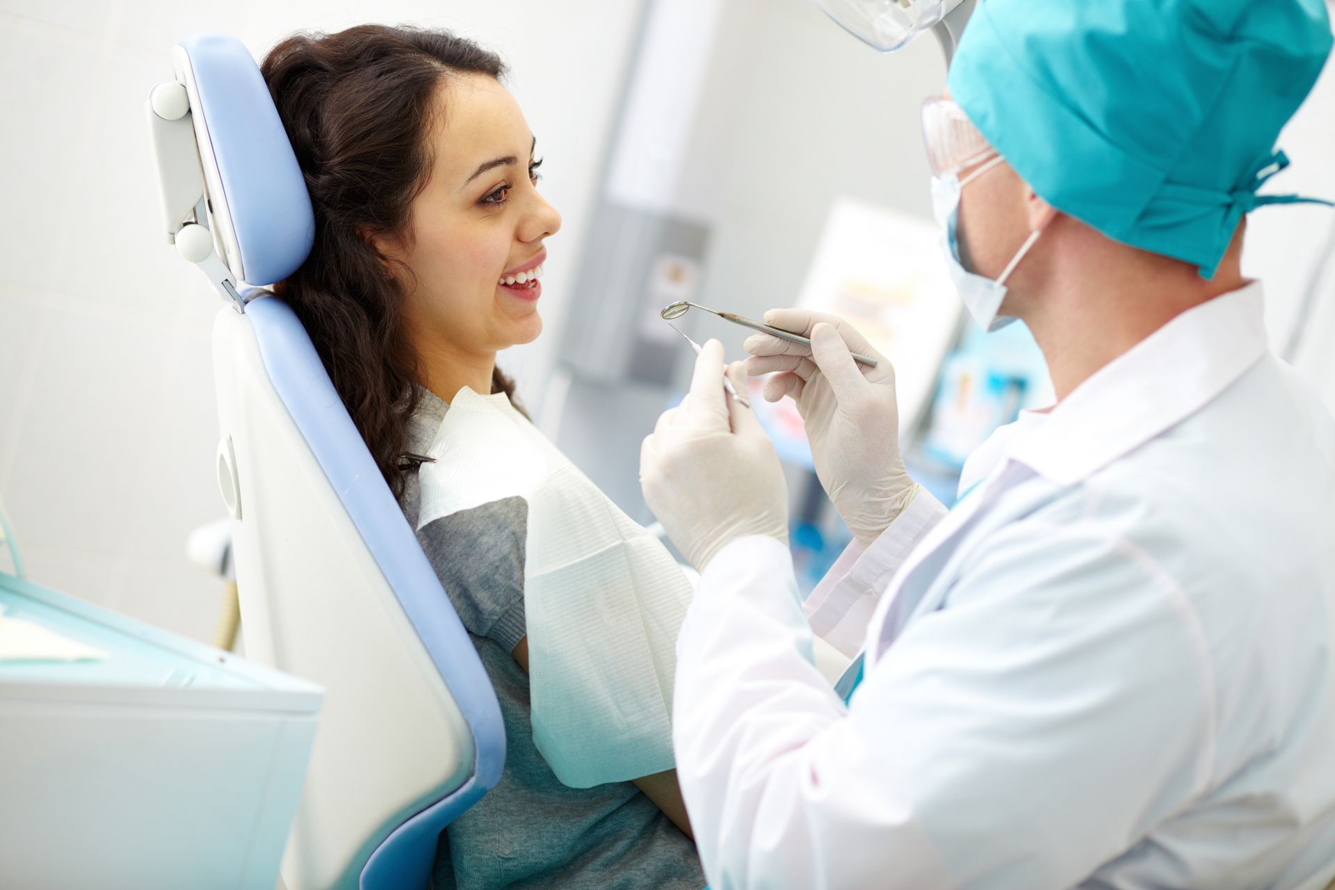 Dentist examining a smiling patient in a dental chair during a checkup