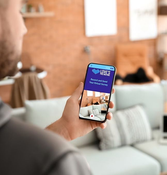 Man holding a smartphone, looking at a website with images of a living room.
