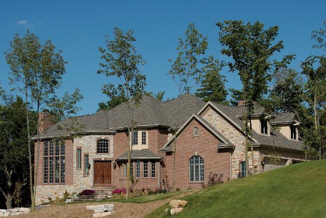 A large brick house sits on top of a grassy hill