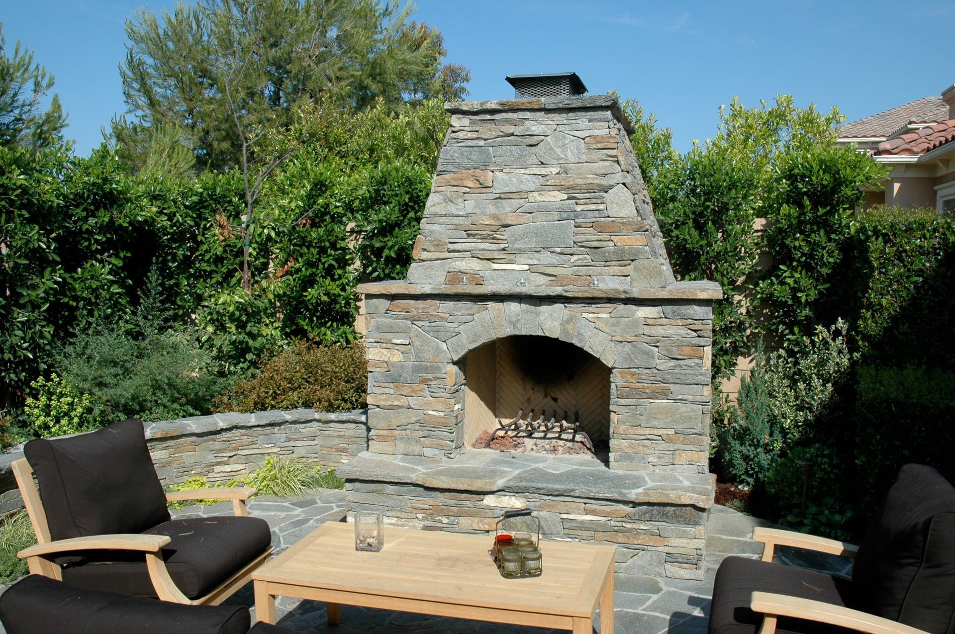A stone fireplace surrounded by chairs and a table