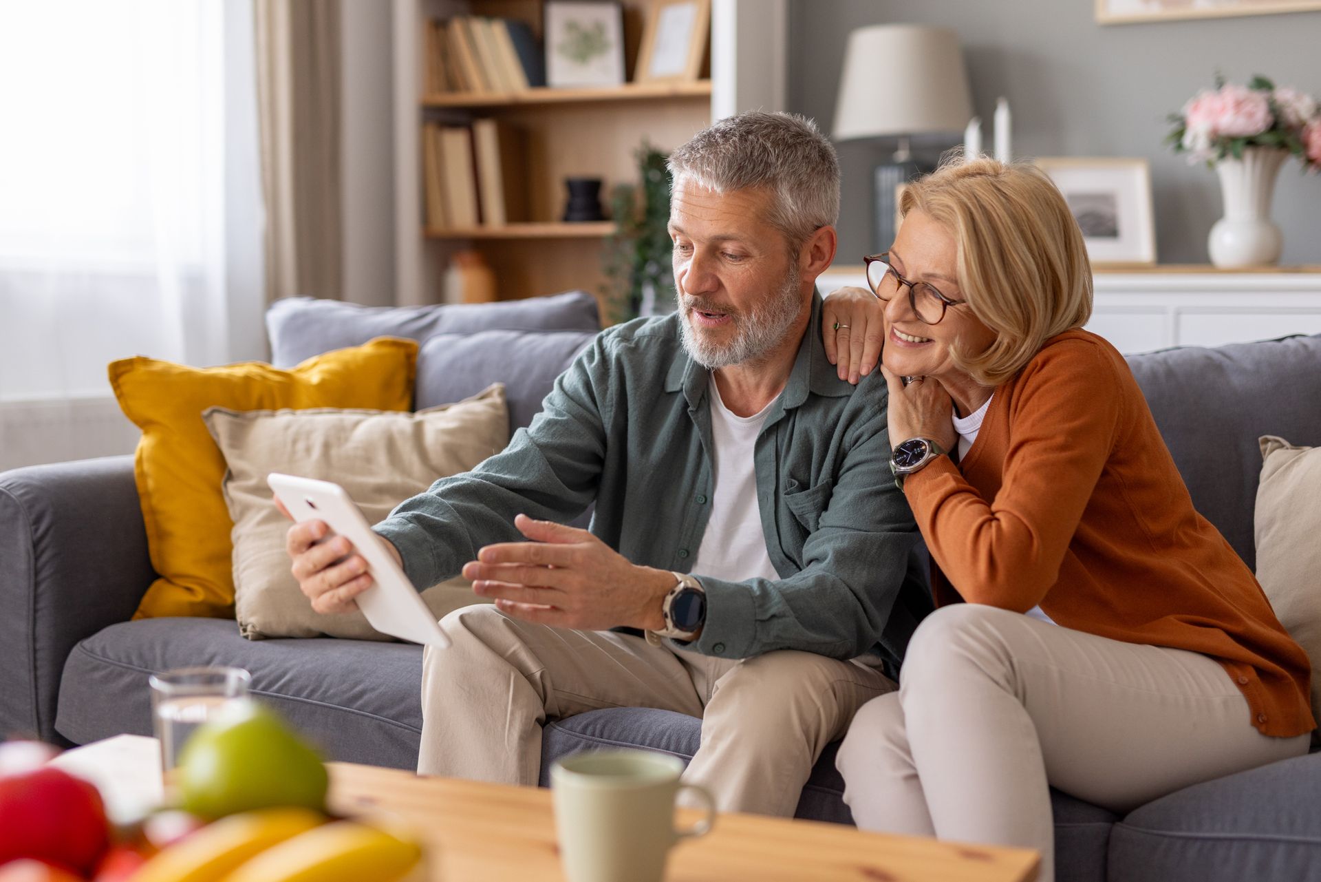 Couple on a couch looking at a tablet in a cozy living room