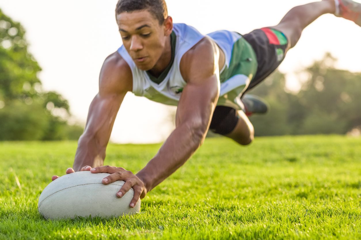 Boy jumping to catch a rugby ball