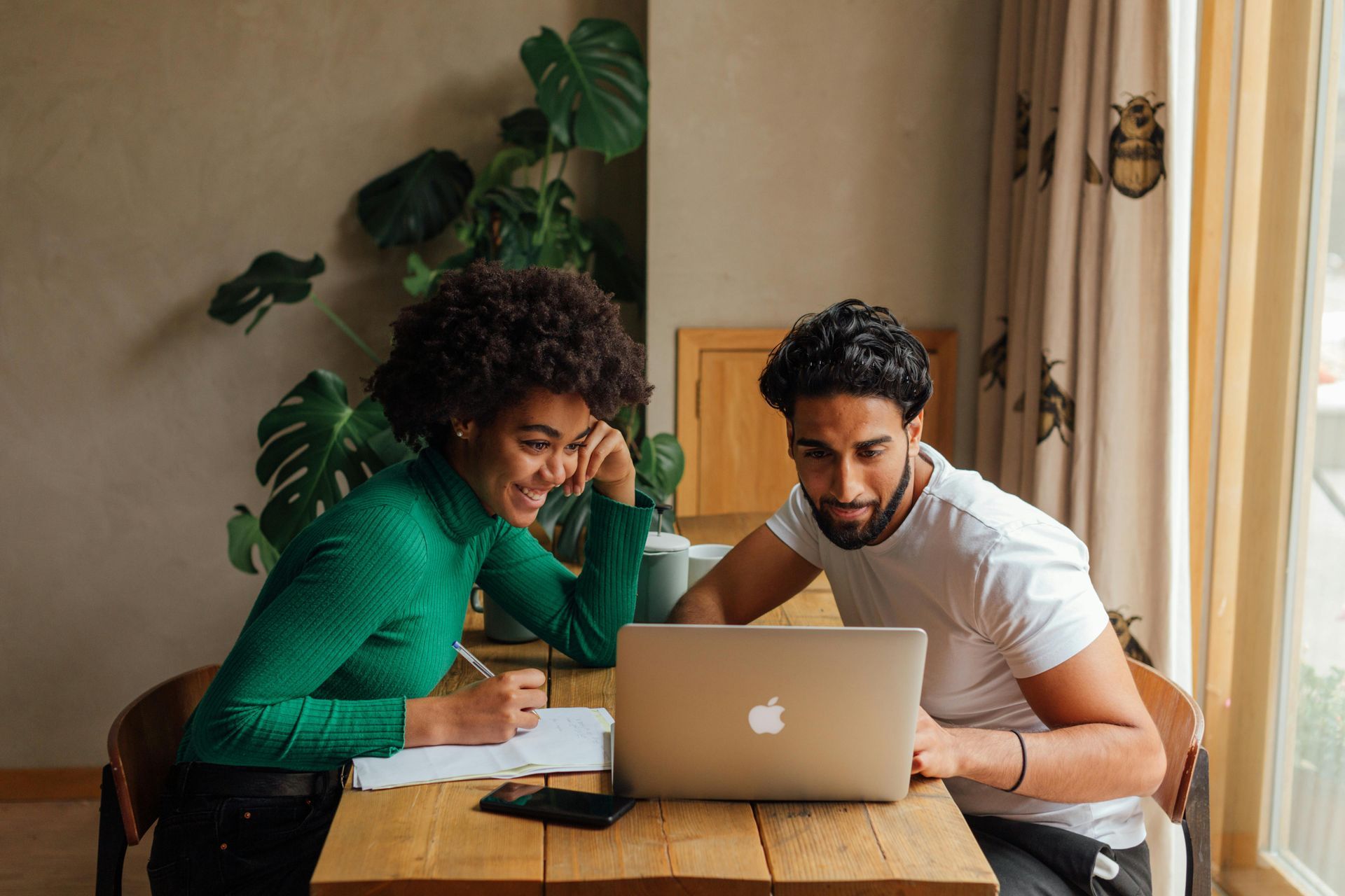 Two professionals reviewing marketing strategy on a laptop at a wooden table, collaborating