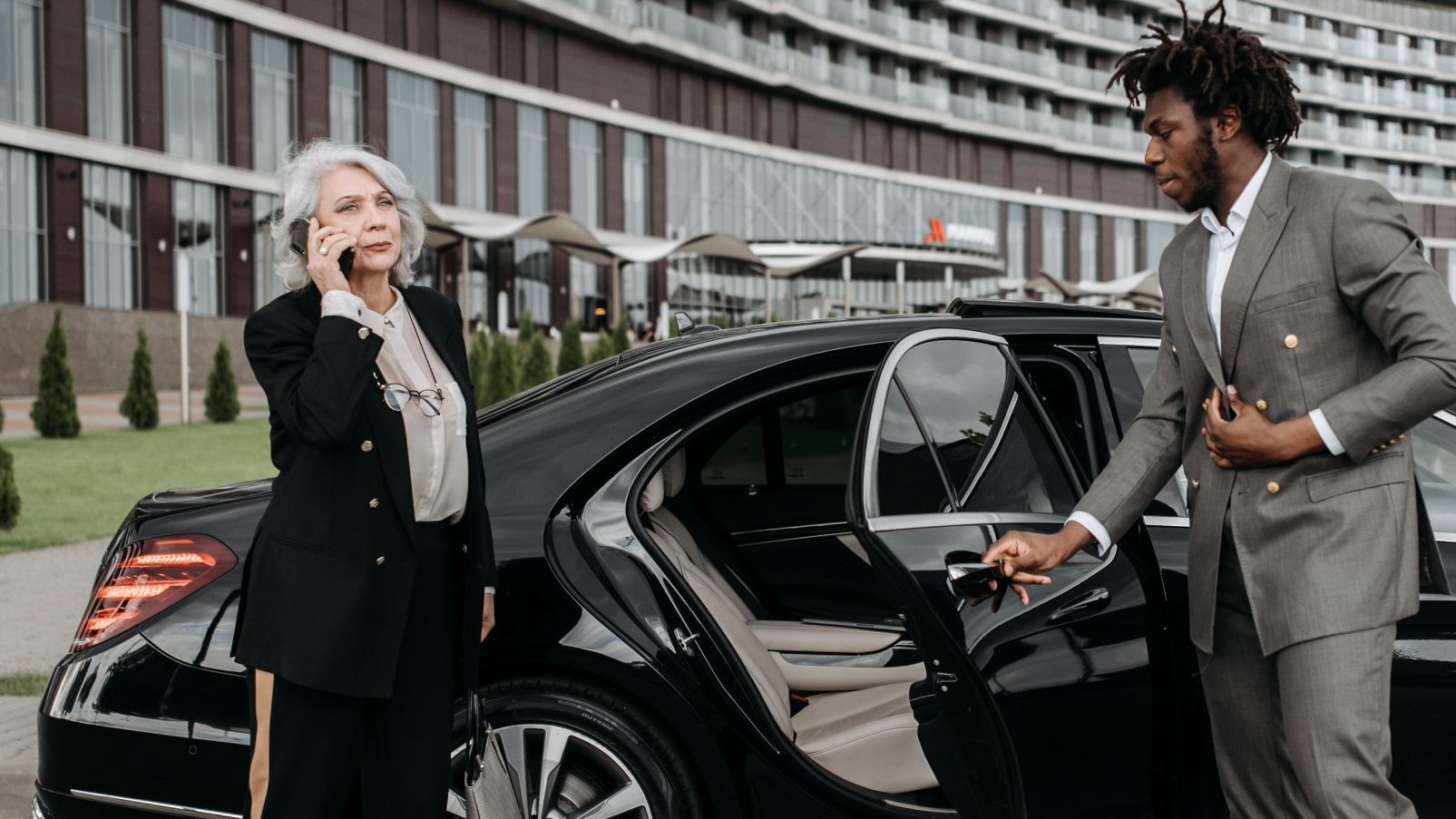 A man in a suit is helping a woman get out of a car.