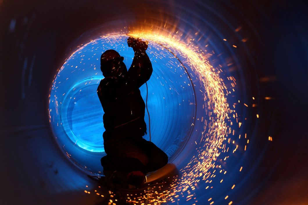 Silhouette of a person kneeling inside a glowing blue tunnel with sparks swirling around them