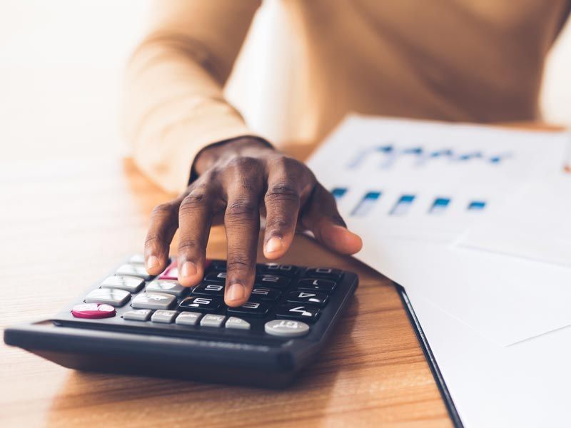 Hand pressing calculator beside a financial chart on a desk