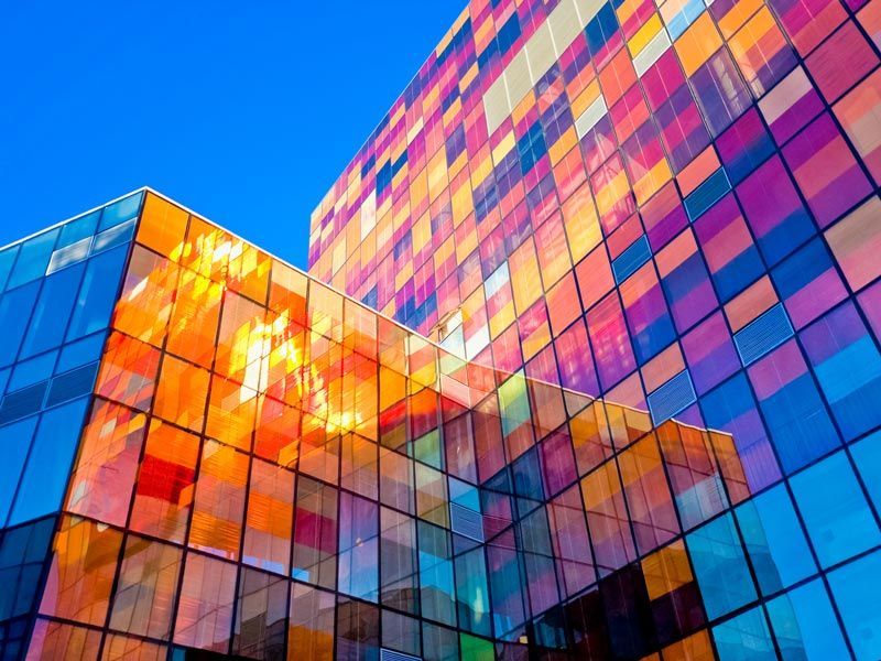 Colorful glass office buildings reflecting warm sunlight against a blue sky