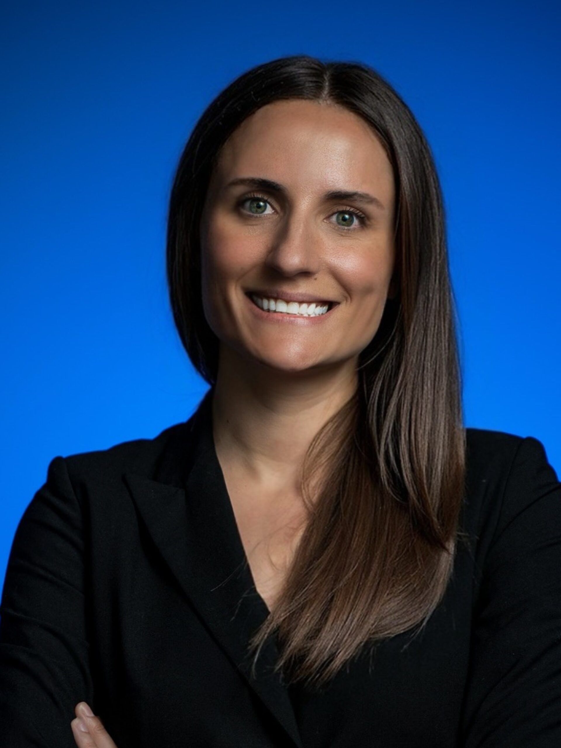 Smiling woman in a black blazer against a blue background