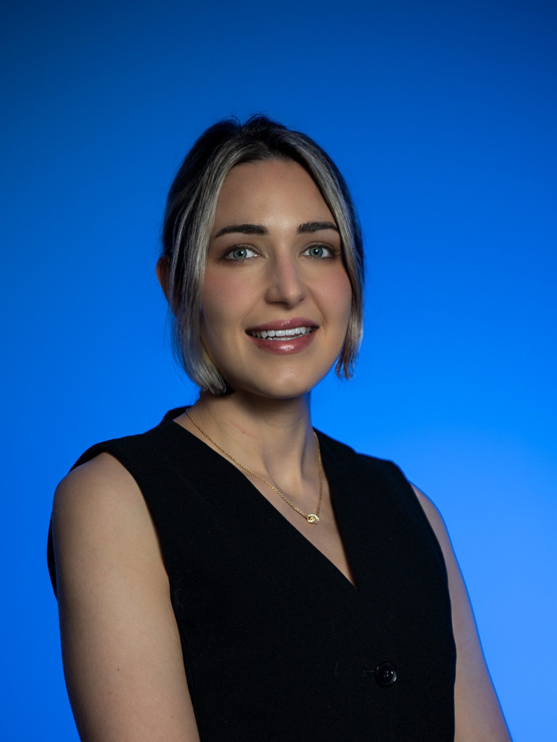 Portrait of a smiling woman in a black dress against a blue background