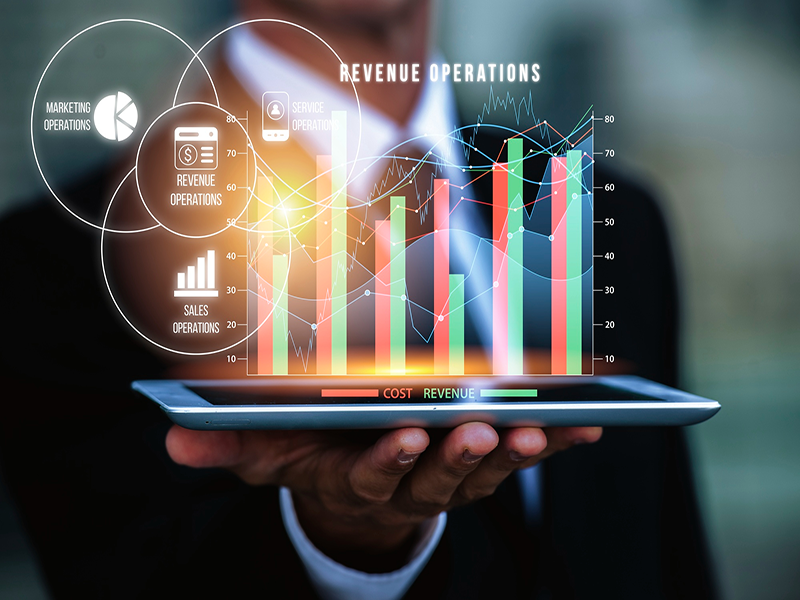 Hand holding a tablet with glowing revenue analytics charts and graphs on screen