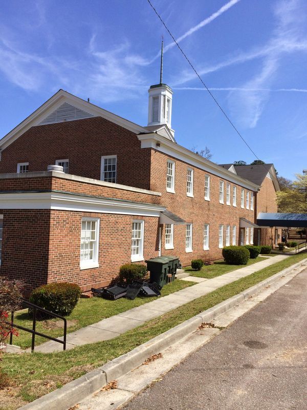 Brick building with a white steeple on a sunny day.