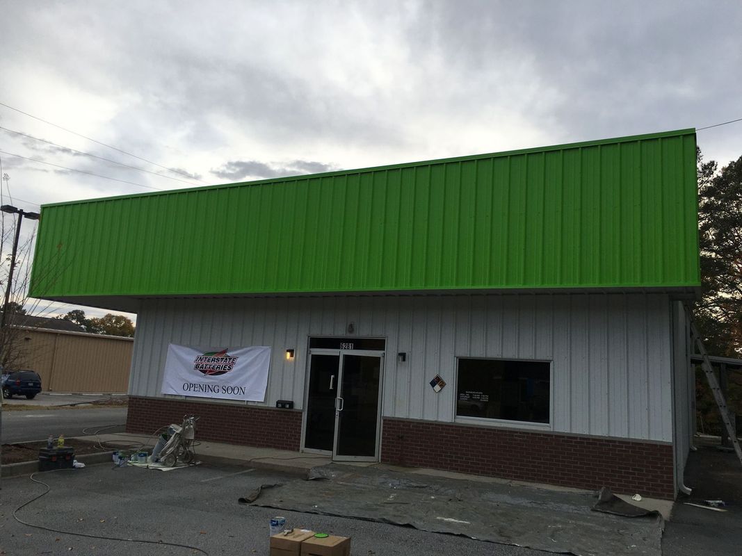 Green and white building with a banner, under a cloudy sky.