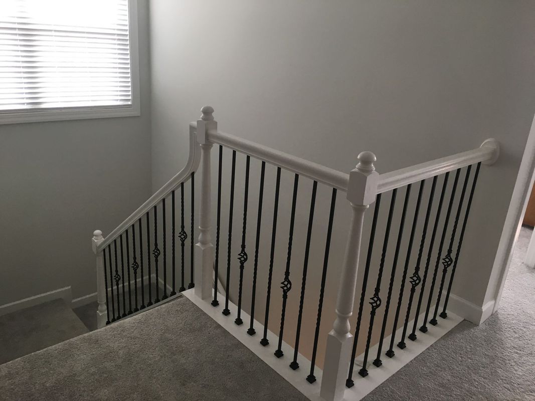Staircase with white railing and black spindles, carpeted stairs, and a window.