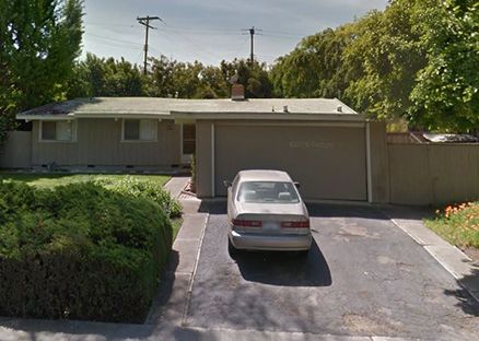 Single-story house with a car parked in the driveway and trees around it