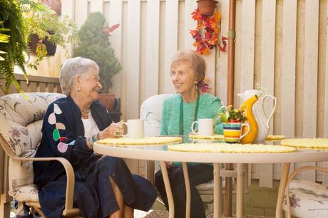 Four smiling people, two older adults and two younger, giving thumbs up outside. Sea backdrop.