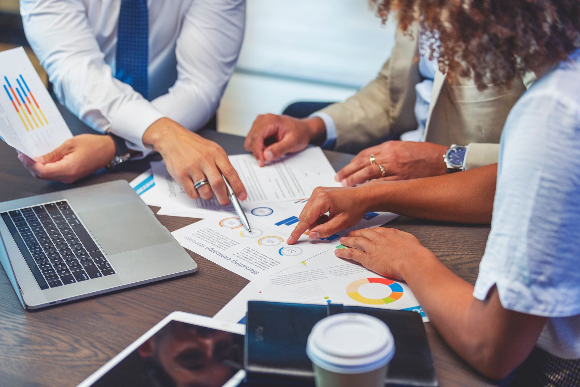 People in business attire review financial charts and graphs at a table.