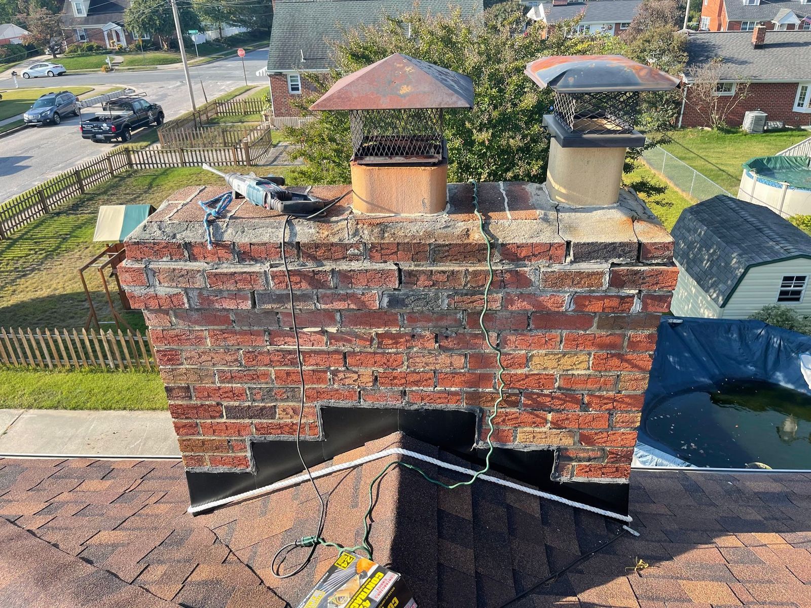 Brick chimney before repair, with worn mortar and a broken crown