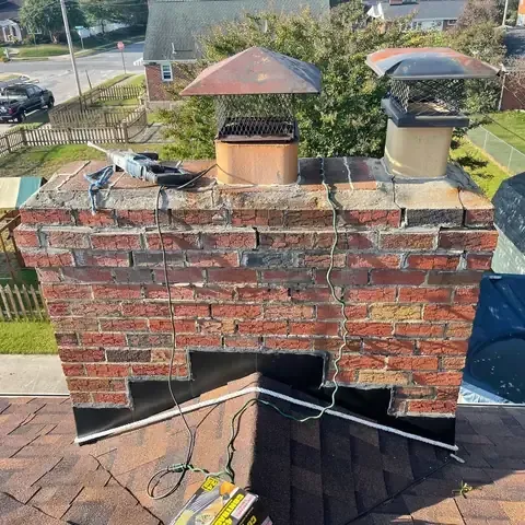 Brick chimney before repair, with worn mortar and a broken crown