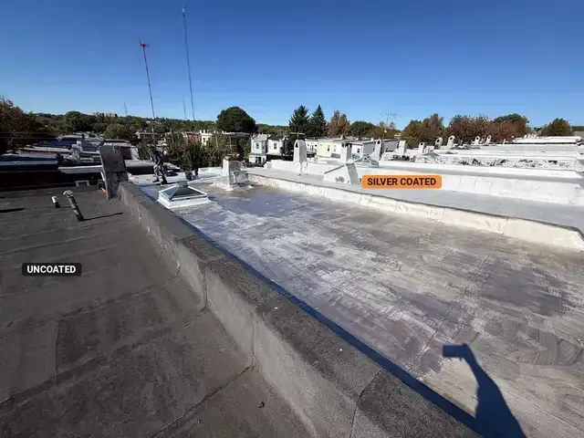 Uncoated modified bitumen flat roof beside a freshly silver coated rowhouse flat roof