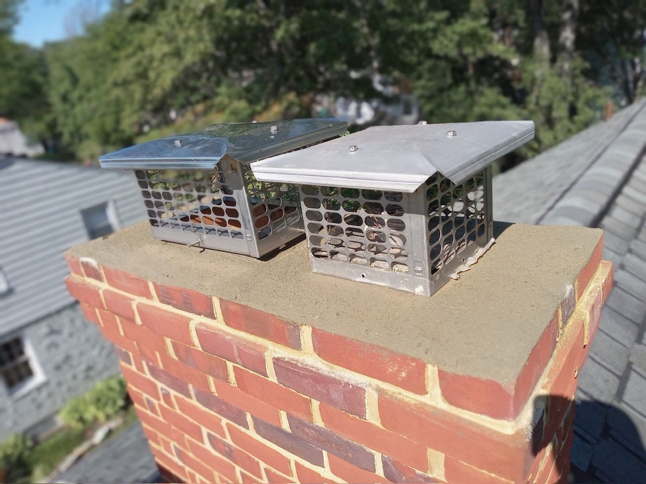 Two chimney caps are sitting on top of a brick chimney.